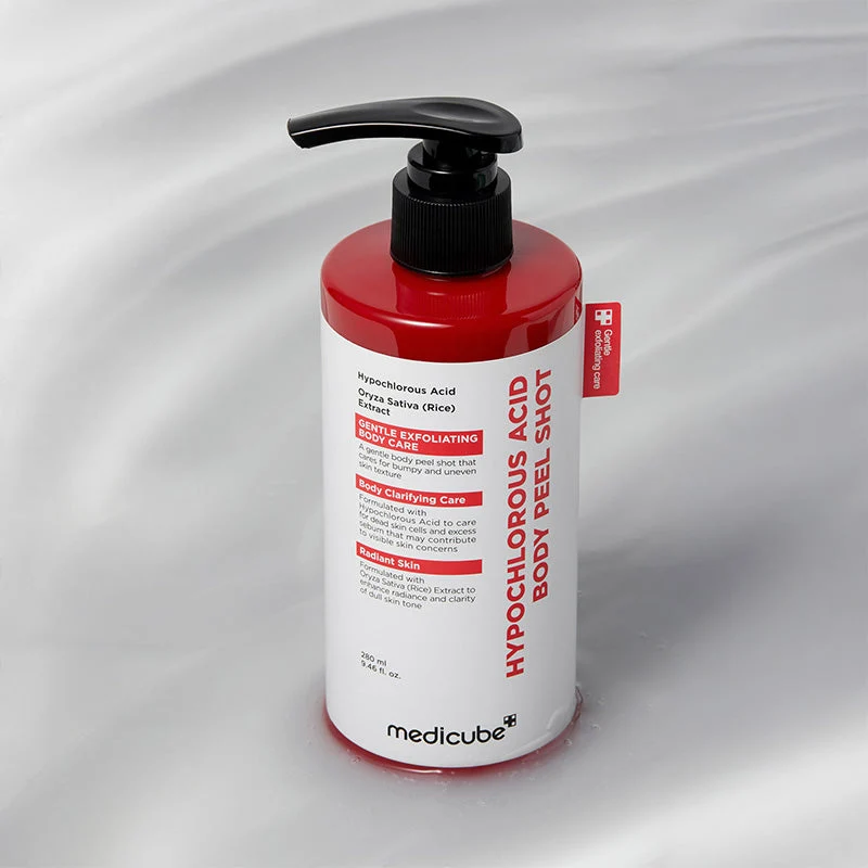 A red and white bottle of Medicube Hypochlorous Acid Body Peel Shot with a black pump cap resting on a wet, rippled surface.