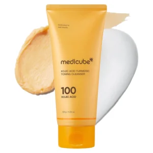 Bright yellow squeeze tube of Medicube Kojic Acid Turmeric Toning Cleanser 100 with swatches of golden paste and rich white foam.