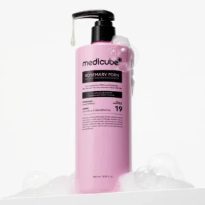 Pink pump bottle of Medicube Rosemary PDRN Cooling Thickening Shampoo surrounded by rich white soapy foam bubbles.